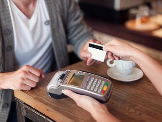 person using bank card to pay in a coffee shop